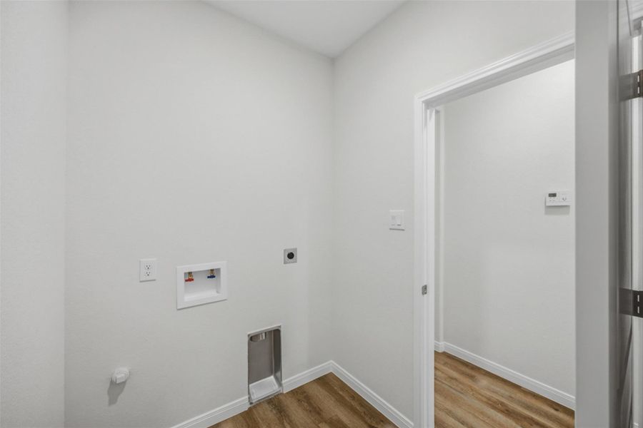 A well-appointed utility room features durable wood flooring and ample space for laundry needs.