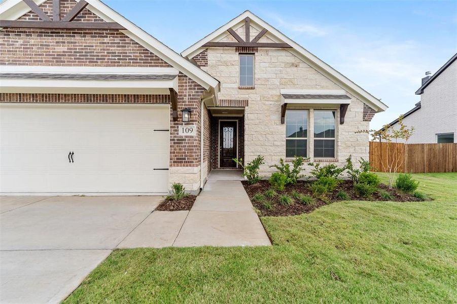 View of front facade with stone siding, driveway, an attached garage, and brick siding View of front facade with stone siding, driveway, an attached garage, and brick siding