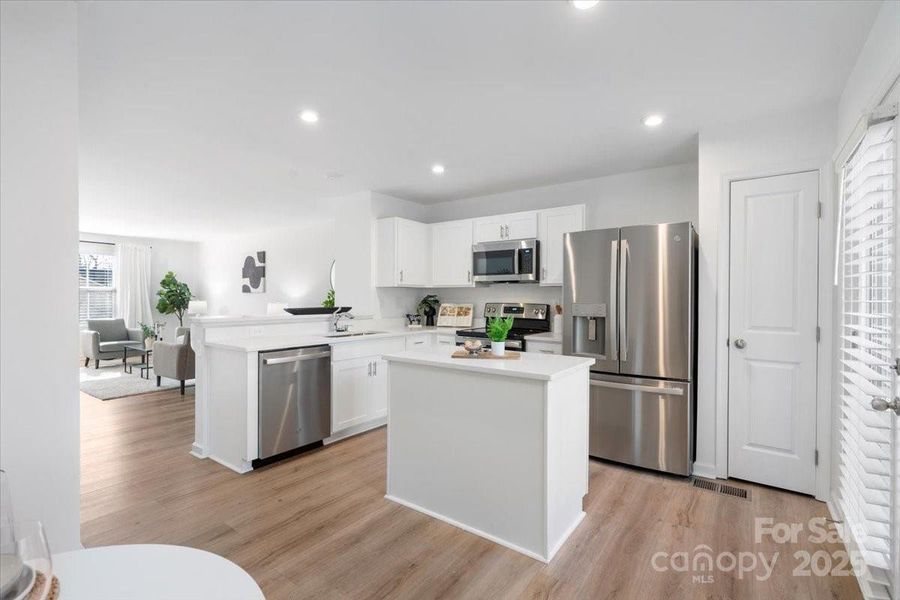 Beautiful kitchen with an island includes bonus cabinet & drawer space, quartz countertops and SS appliances. There's custom shelving in the pantry too.