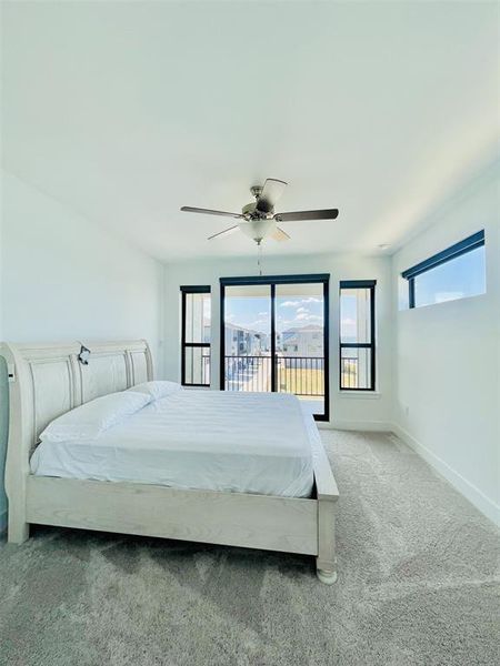 Carpeted bedroom featuring multiple windows, ceiling fan, and access to outside Carpeted bedroom featuring multiple windows, ceiling fan, and access to outside