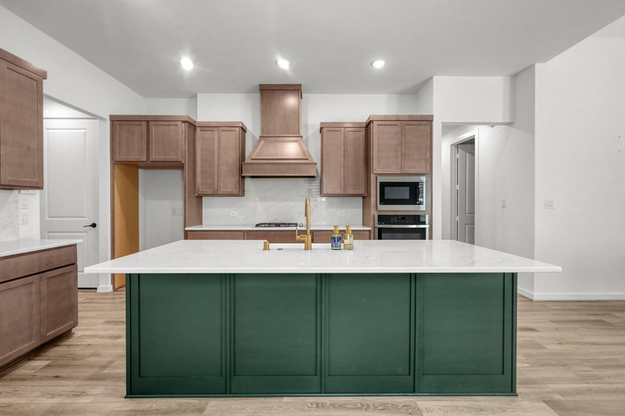 This beautiful kitchen features warm wood toned cabinets and the island is a deep green accent color. Lots of counter and storage space in the kitchen.