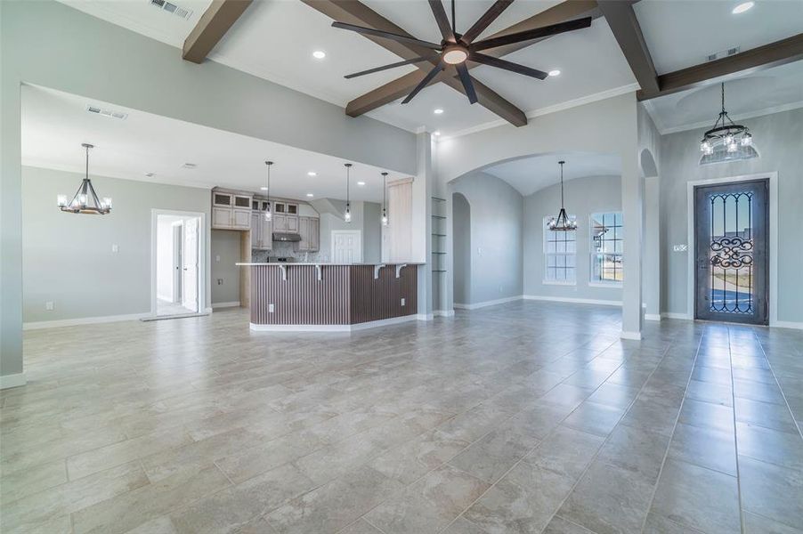 Unfurnished living room with a chandelier, ornamental molding, beam ceiling, arched walkways, and recessed lighting Unfurnished living room with a chandelier, ornamental molding, beam ceiling, arched walkways, and recessed lighting