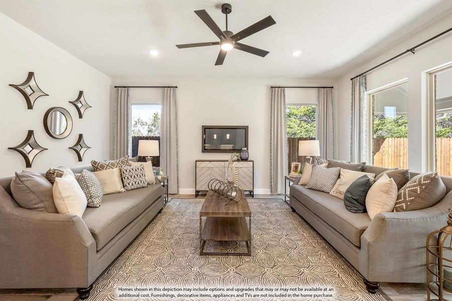 Living room with two gray sofas, ceiling fan, patterned area rug, and large windows with natural light Living room with two gray sofas, ceiling fan, patterned area rug, and large windows with natural light