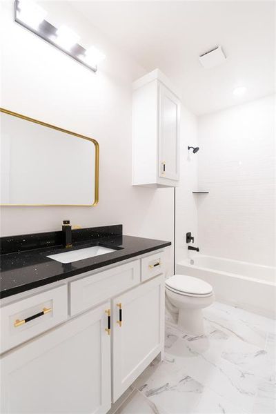 Bathroom with washtub / shower combination, marble finish floor, toilet, and vanity Bathroom with washtub / shower combination, marble finish floor, toilet, and vanity