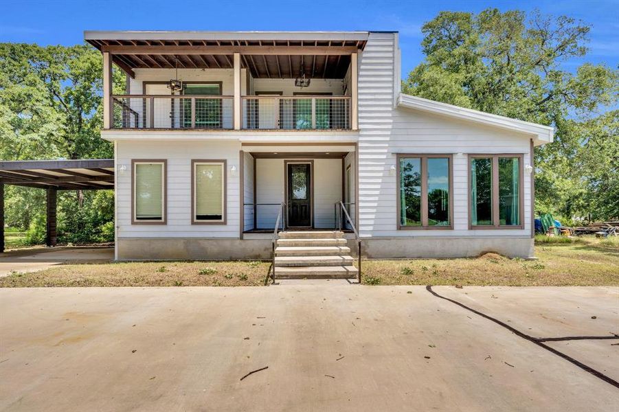 View of front of home with a balcony, a carport, and covered porch