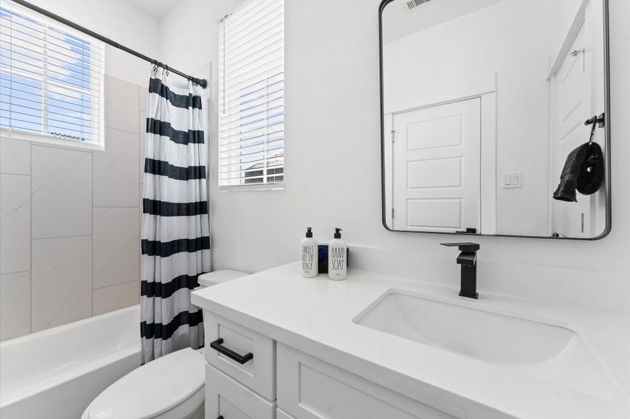 his well-appointed secondary bathroom features a classic tub and shower combo, ideal for both quick rinses and leisurely soaks.