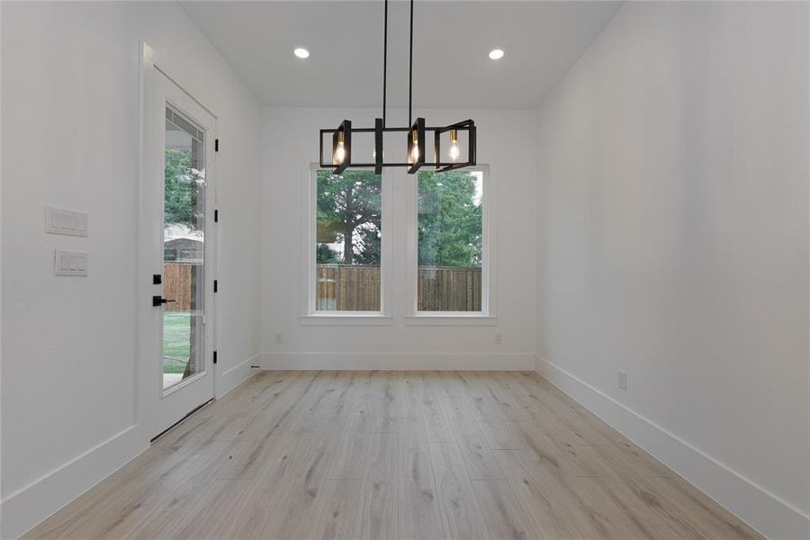 Unfurnished dining area with light wood finished floors, a chandelier, and recessed lighting
