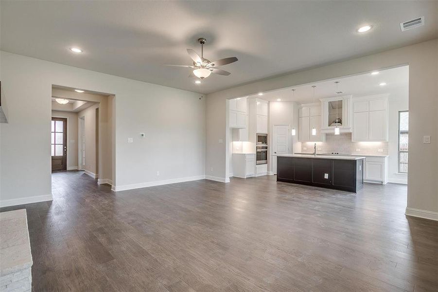 Unfurnished living room with dark wood-type flooring, ceiling fan, and sink