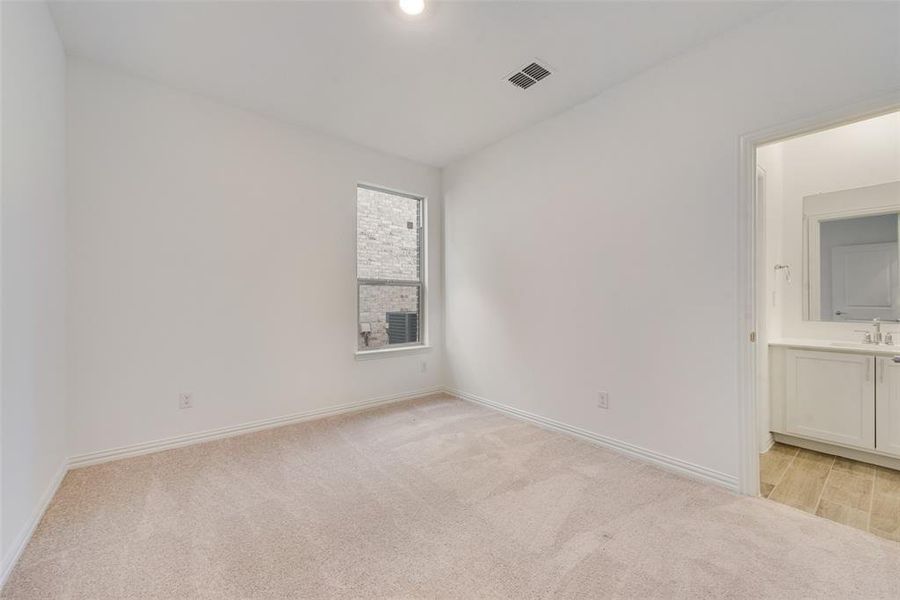 Unfurnished bedroom featuring connected bathroom, sink, and light colored carpet