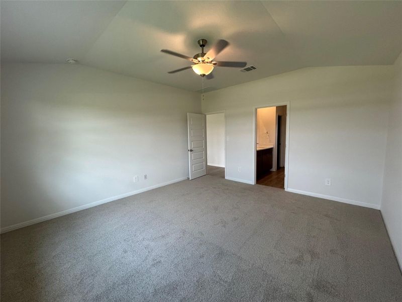 Unfurnished bedroom featuring vaulted ceiling, carpet flooring, a ceiling fan, and connected bathroom Unfurnished bedroom featuring vaulted ceiling, carpet flooring, a ceiling fan, and connected bathroom