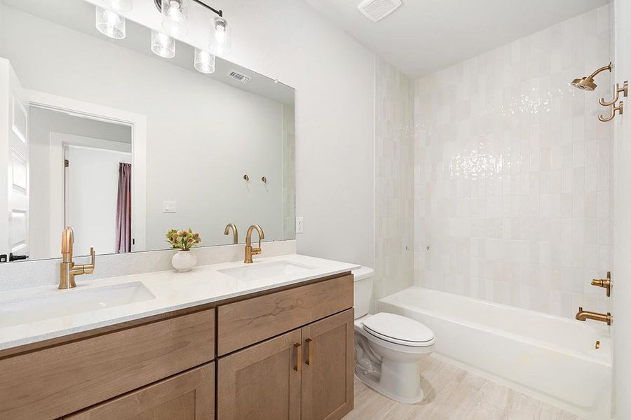Modern finishes define this bathroom highlighting a double vanity and sleek tiled tub surround.