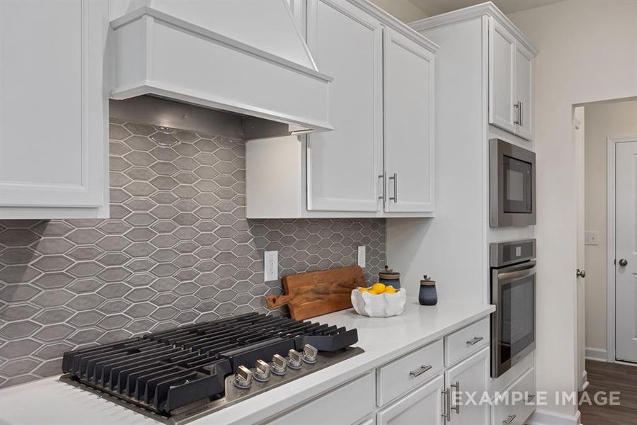 Kitchen with white cabinets, premium range hood, tasteful backsplash, and stainless steel appliances