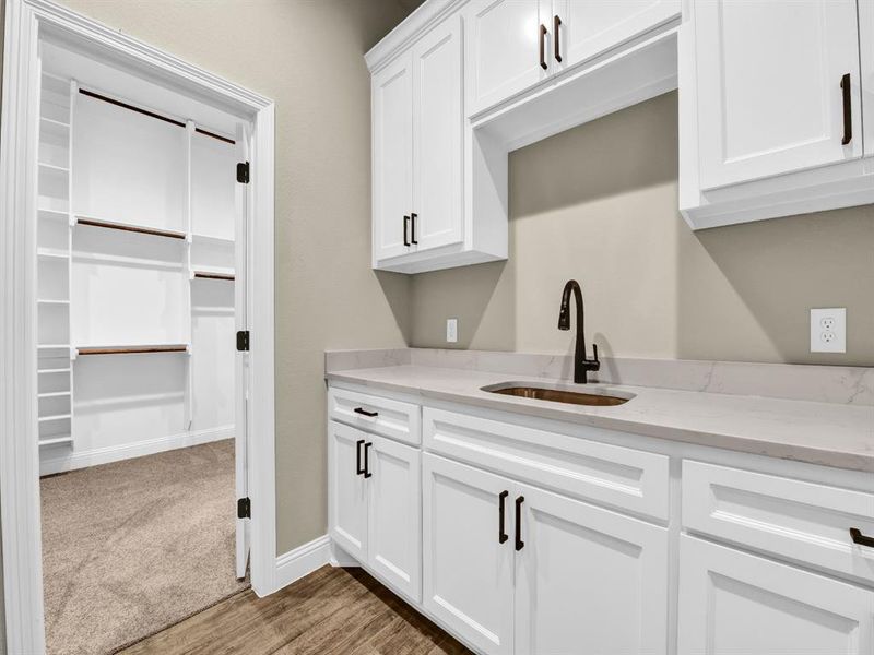 Kitchen with sink, white cabinetry, light stone counters, and carpet floors