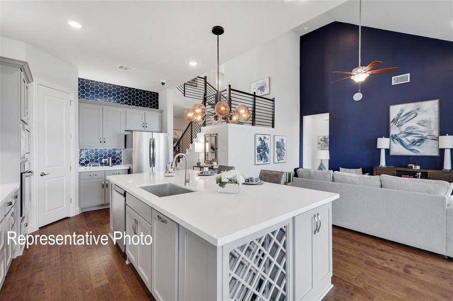 Kitchen with stainless steel fridge, a center island with sink, dark hardwood / wood-style flooring, backsplash, and sink