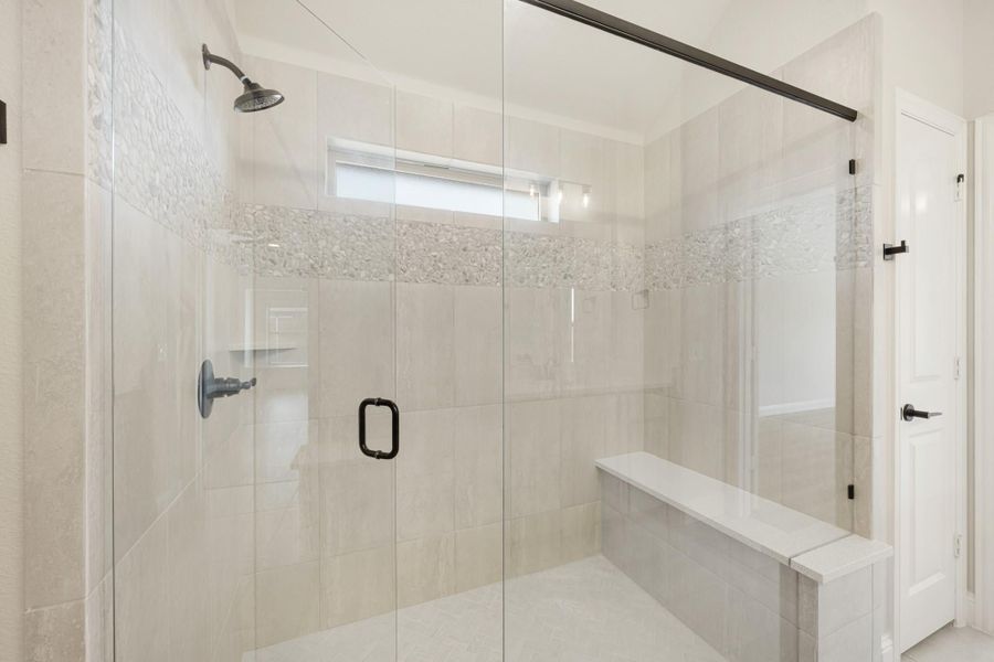 Walk-in shower with glass doors, tile walls, built-in bench, and mosaic accent strip