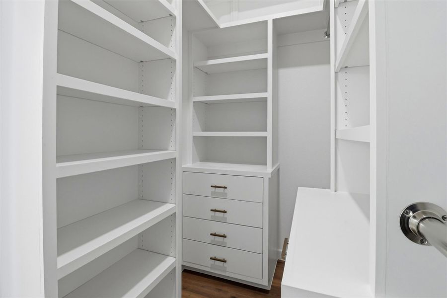 Custom white built-in closet system featuring adjustable shelving, integrated drawers with brass hardware, and hanging rods Custom white built-in closet system featuring adjustable shelving, integrated drawers with brass hardware, and hanging rods