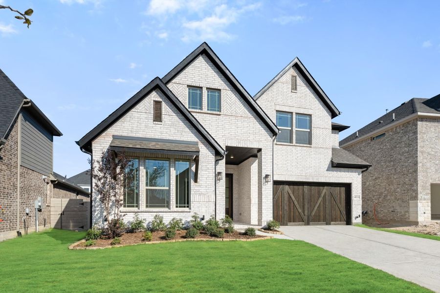 Two-story home with white brick exterior, dark wood garage door, and manicured front lawn