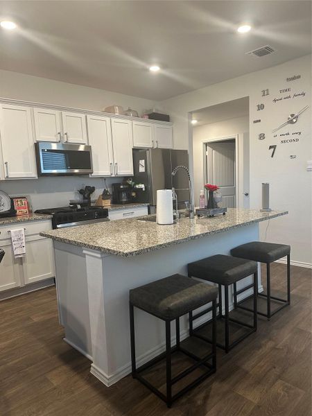 Kitchen featuring a breakfast bar area, light stone countertops, dark wood-type flooring, and recessed lighting