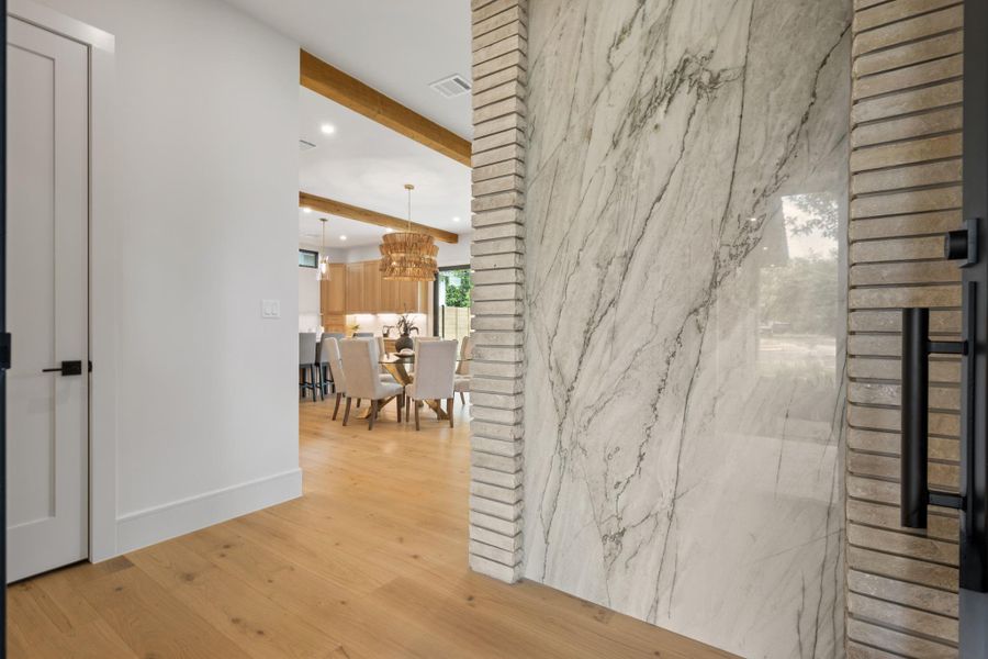 An inviting entrance foyer reveals rich wood floors and exposed ceiling beams beyond.