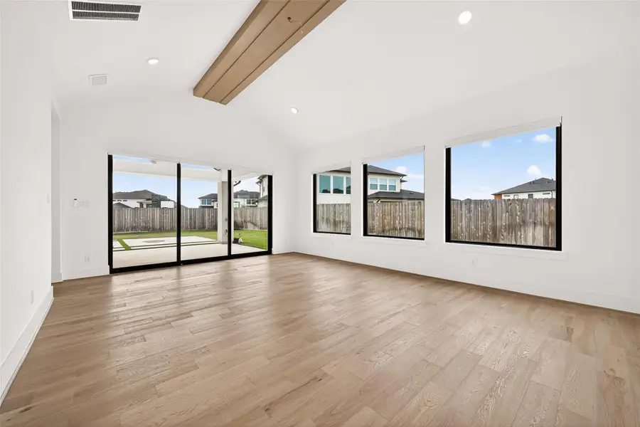 Game Room: At the rear of the home, the spacious game room offers soaring ceilings, recessed lighting, three oversized windows overlooking the backyard, and sliding glass doors with direct pool access.