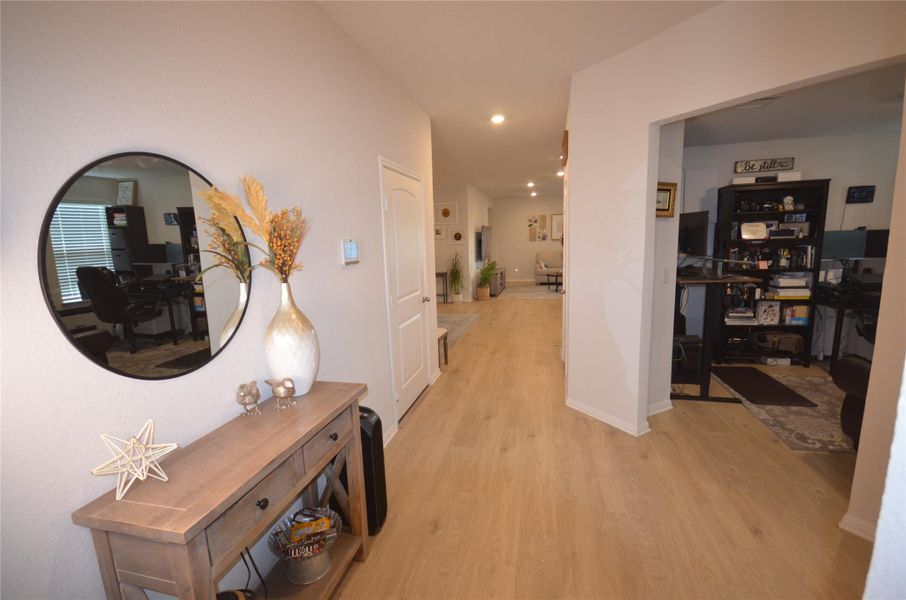 Hallway with light wood finished floors, a desk, and recessed lighting Hallway with light wood finished floors, a desk, and recessed lighting