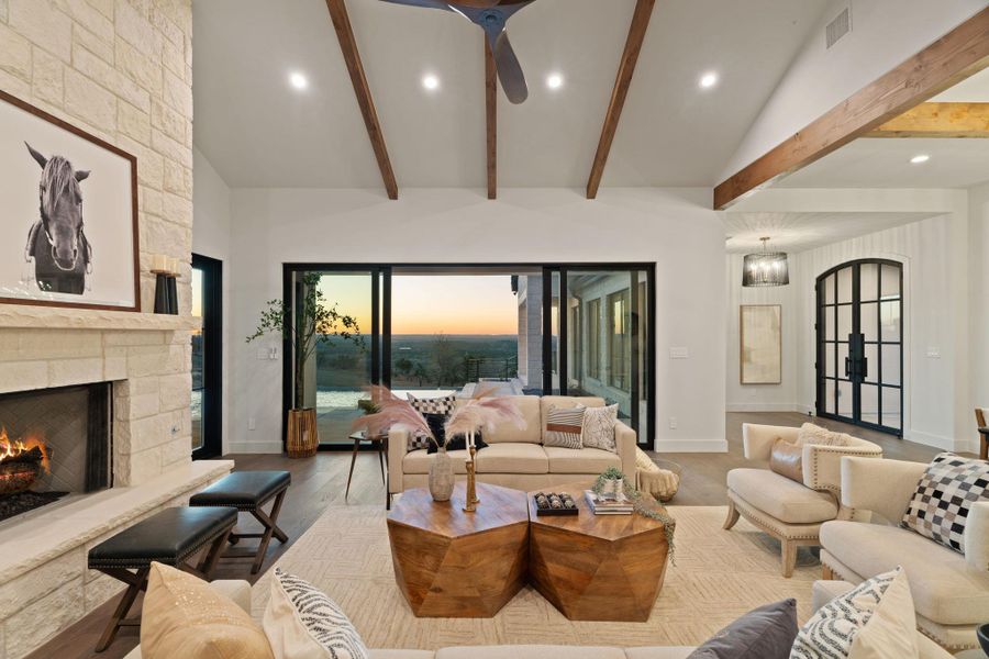 Living area featuring a stone fireplace, recessed lighting, vaulted ceiling, and wood finished floors with views of outdoor living and hill country.