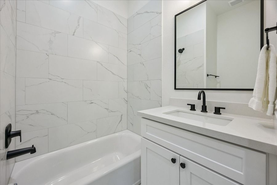 The ensuite first-floor bath showcases stylish tile, quartz countertops, and a tub/shower combination. The ensuite first-floor bath showcases stylish tile, quartz countertops, and a tub/shower combination.