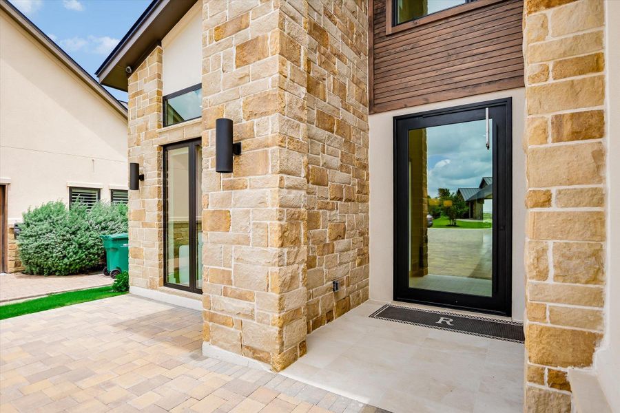 A sophisticated home entrance with a paver walkway and natural stone facade welcomes you.