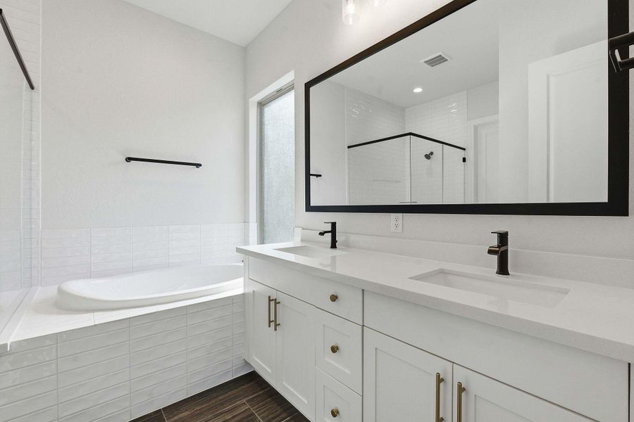 Bathroom with double vanity, wood finish floors, a bath, and a shower stall