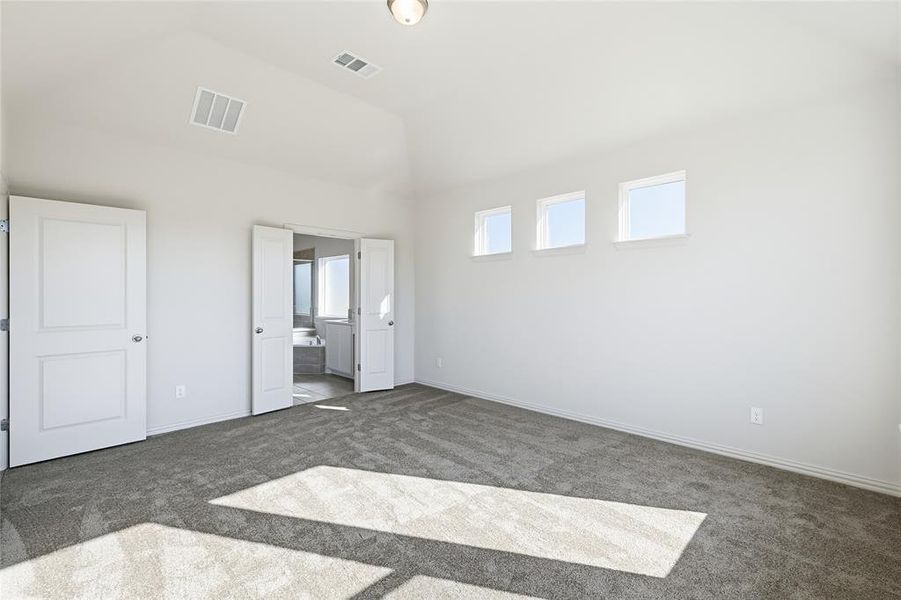 Unfurnished bedroom featuring connected bathroom, lofted ceiling, and carpet