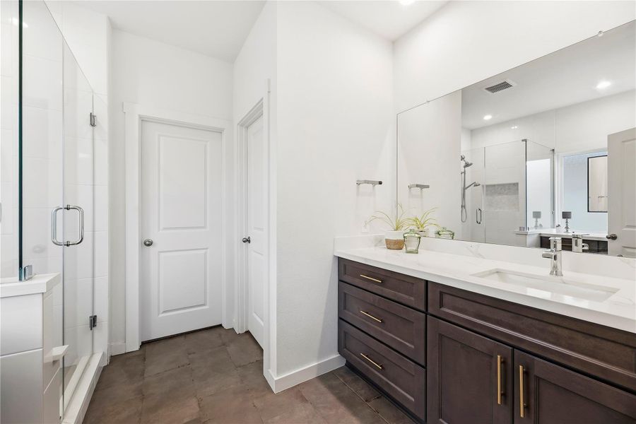 Redesigned primary bathroom with separate vanities, ample drawer storage and a wide framed mirror.