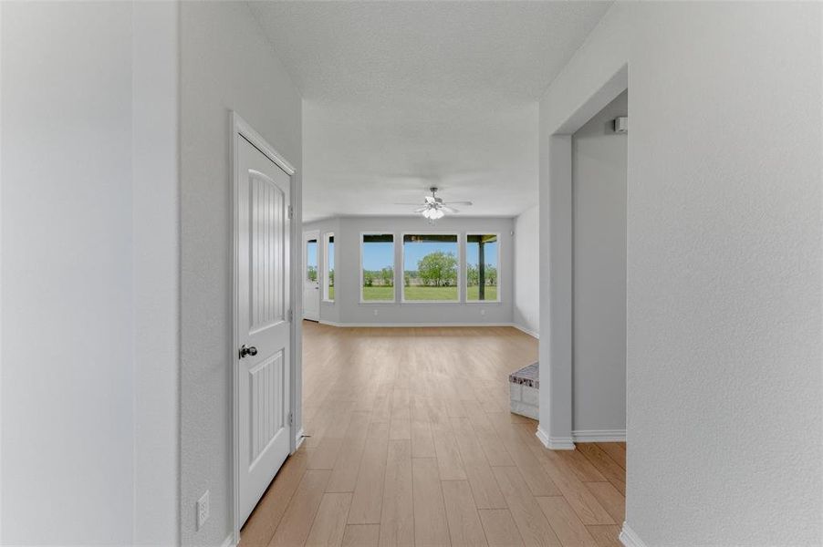 Open concept living space featuring light wood-finish flooring, a contemporary ceiling fan, and multiple large windows Open concept living space featuring light wood-finish flooring, a contemporary ceiling fan, and multiple large windows