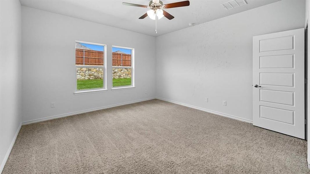 Empty room with light colored carpet and a ceiling fan
