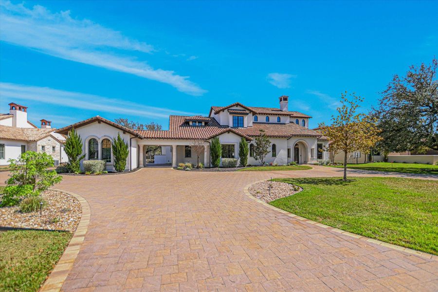 Mediterranean / spanish house with stucco siding, a front lawn, and curved driveway