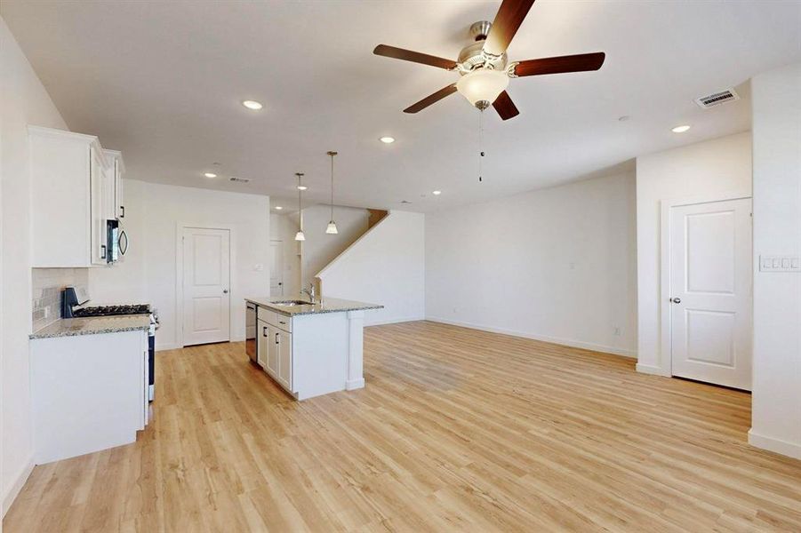 Kitchen featuring white cabinets, recessed lighting, light stone countertops, and decorative light fixtures
