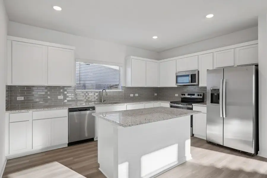 Kitchen featuring appliances with stainless steel finishes, white cabinetry, light stone countertops, light wood-style flooring, and recessed lighting
