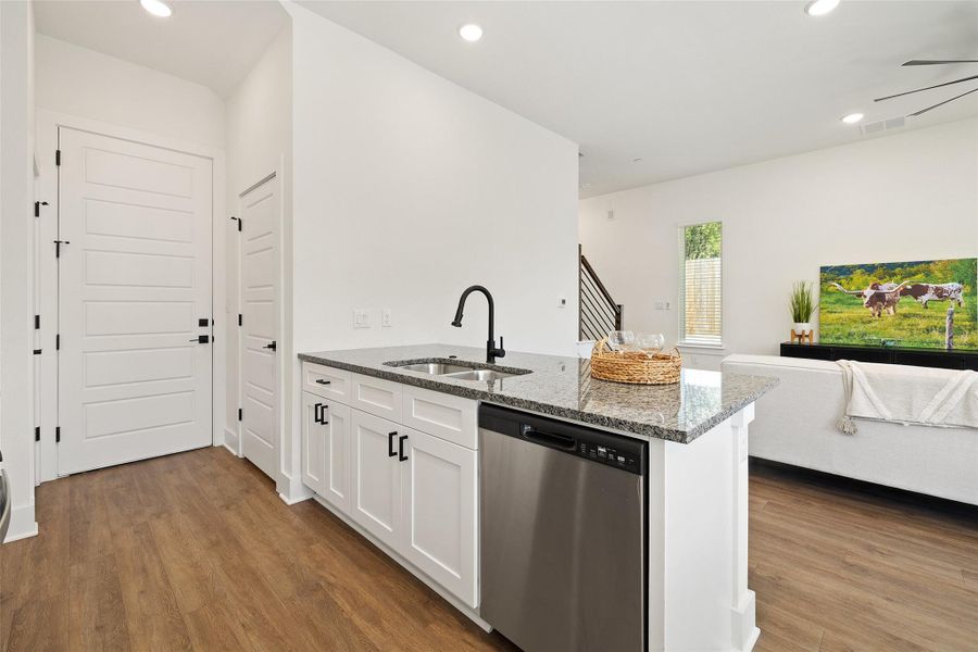 Kitchen with recessed lighting, dishwasher, stone countertops, open floor plan, and white cabinets Kitchen with recessed lighting, dishwasher, stone countertops, open floor plan, and white cabinets