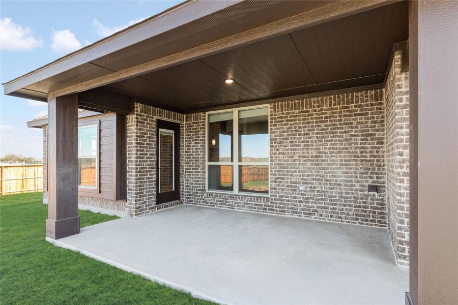 Covered back patio with concrete floor, brick exterior, dark wood ceiling, and door leading inside Covered back patio with concrete floor, brick exterior, dark wood ceiling, and door leading inside