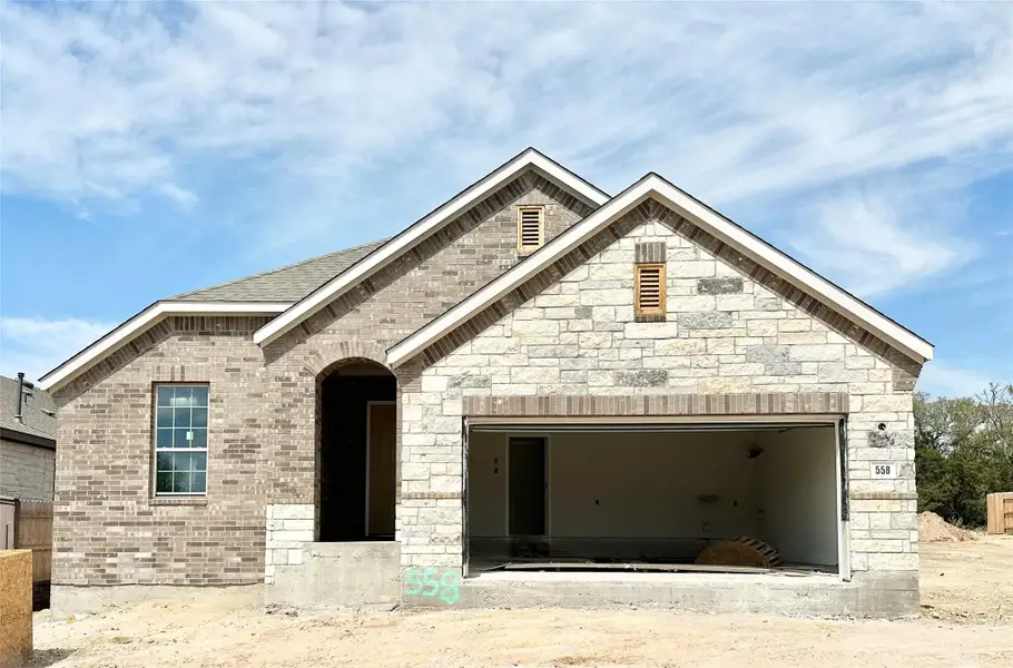 French provincial home featuring brick siding, stone siding, and an attached garage French provincial home featuring brick siding, stone siding, and an attached garage