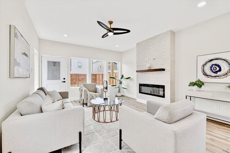 Living area featuring a white brick fireplace with a wood mantle and a linear electric insert