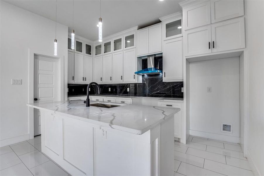 Kitchen with decorative backsplash, glass insert cabinets, and light stone counters