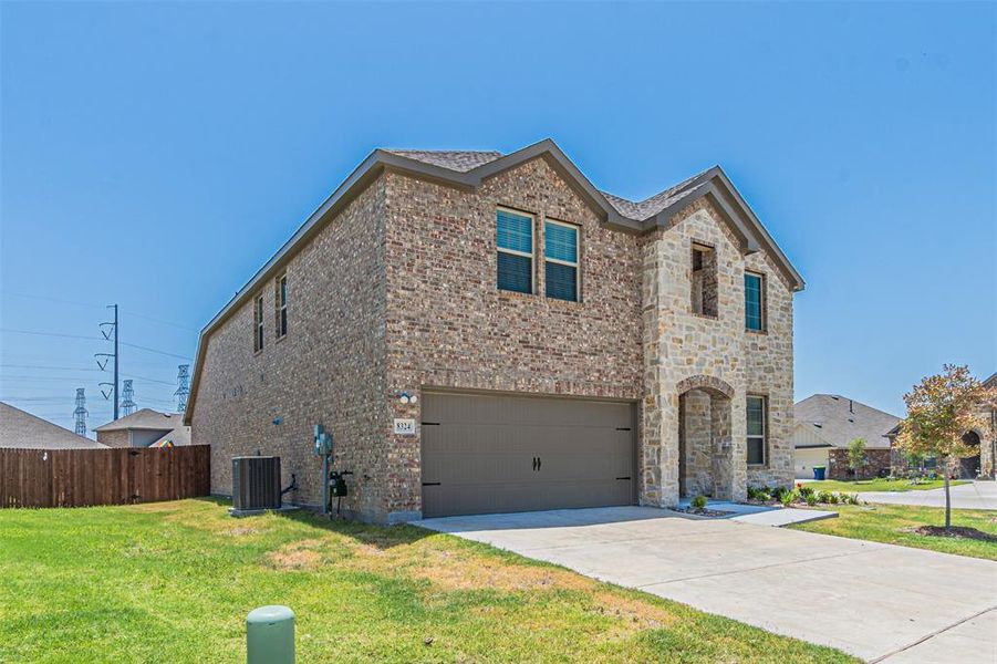 View of front of house featuring a garage, central air condition unit, and a front lawn