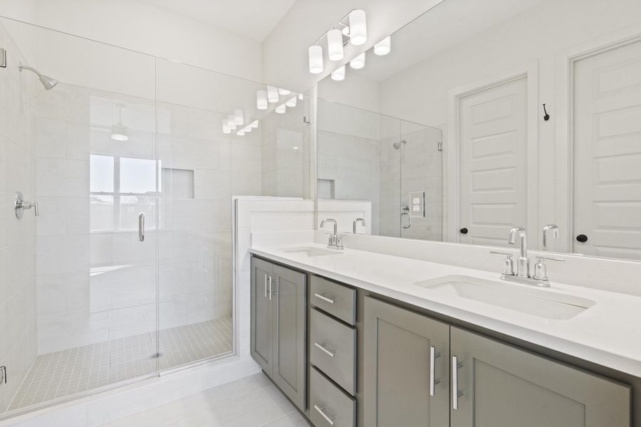 Bathroom featuring double vanity, a stall shower, and light tile patterned floors