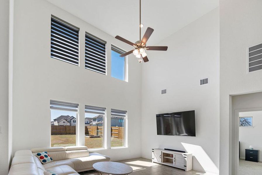 Living area featuring a ceiling fan and a high ceiling Living area featuring a ceiling fan and a high ceiling