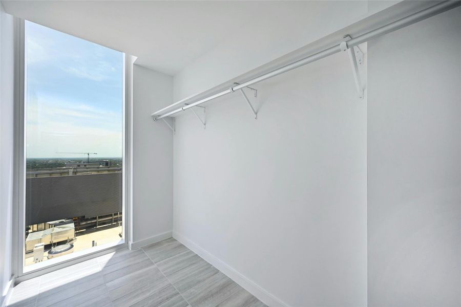 Bright and spacious walk-in closet with floor-to-ceiling window, offering natural light and skyline views—perfect for a stylish start to the day.