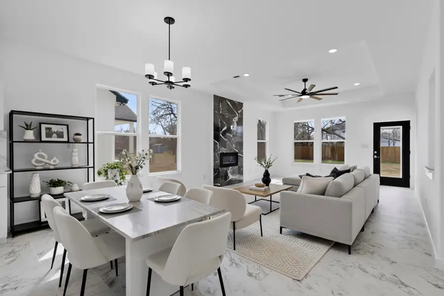 Dining space featuring a tray ceiling, ceiling fan, and electric fireplace, and hanging lights