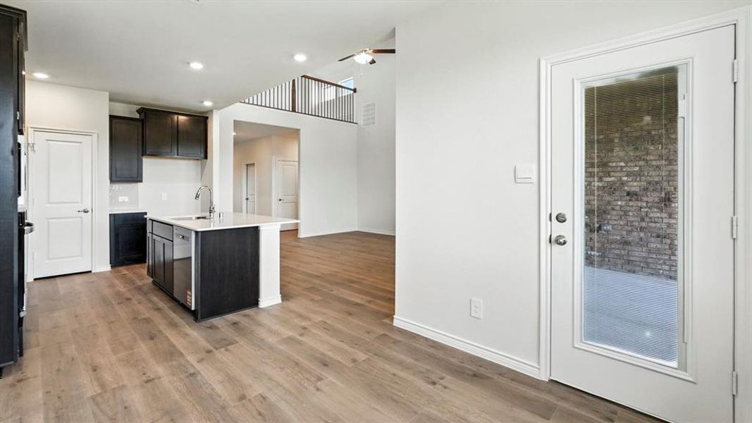 Kitchen with a center island with sink, light wood-style floors, light stone countertops, and recessed lighting