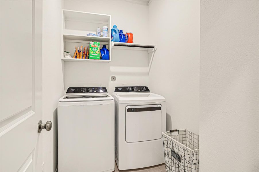Modern laundry room equipped with a washer and dryer, ample shelving for storage, and a convenient laundry basket. Modern laundry room equipped with a washer and dryer, ample shelving for storage, and a convenient laundry basket.