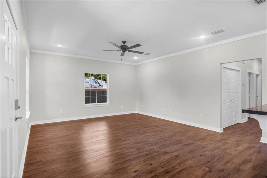 Unfurnished room with a ceiling fan, dark wood finished floors, baseboards, recessed lighting, and crown molding