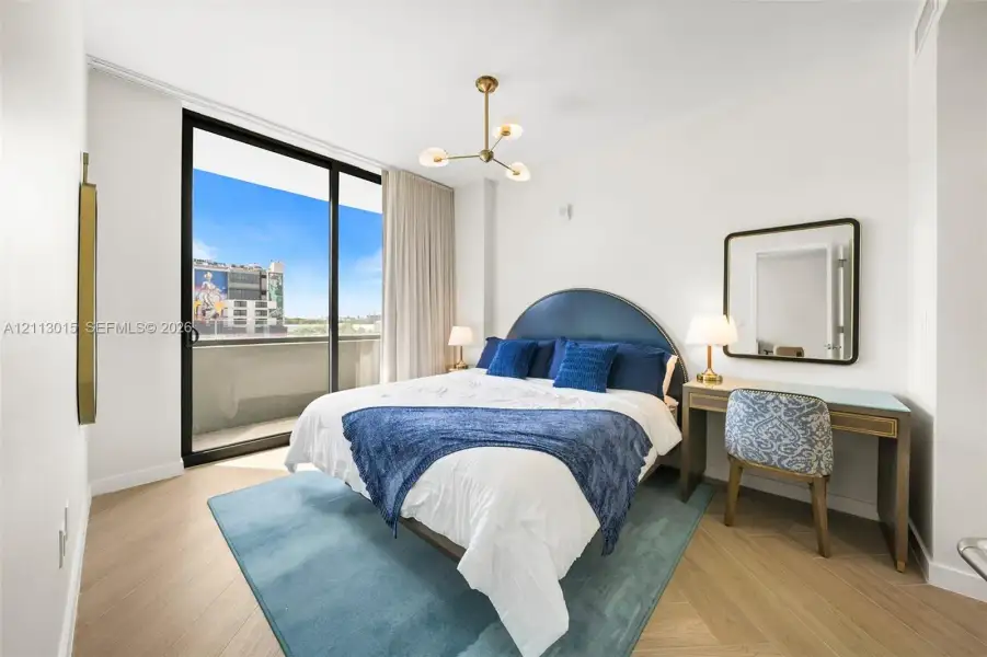 Herringbone-patterned wood-finish flooring, floor-to-ceiling sliding glass doors, private balcony, and contemporary multi-arm chandelier